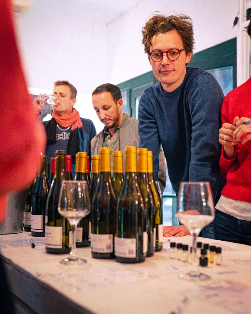 Équipe autour d'une table de dégustation : bouteilles, flacons d'arômes et verres